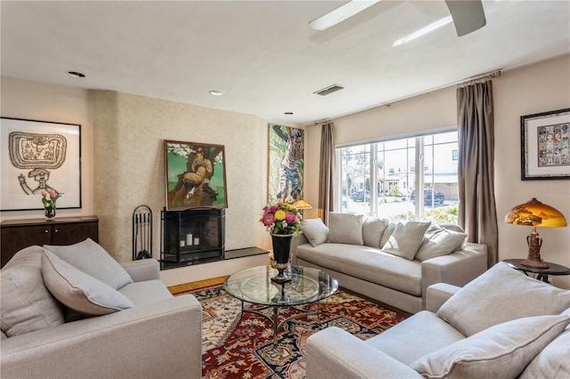 living area with ceiling fan and a fireplace