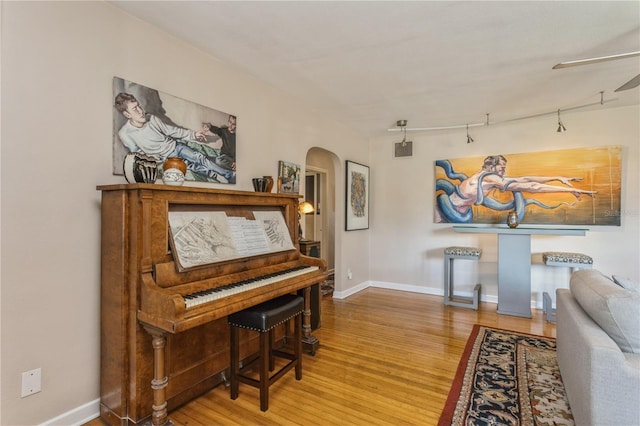 living area featuring arched walkways, visible vents, baseboards, and wood finished floors