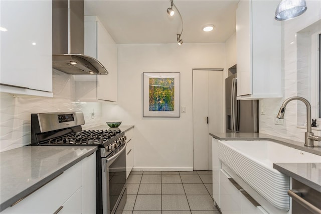 kitchen with wall chimney exhaust hood, backsplash, stainless steel range with gas stovetop, and white cabinetry