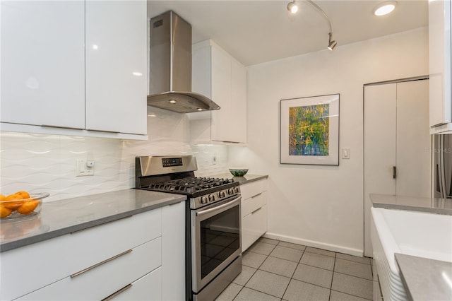 kitchen with backsplash, white cabinetry, stainless steel gas range oven, and wall chimney exhaust hood