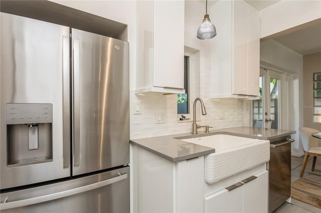 kitchen featuring white cabinetry, appliances with stainless steel finishes, light stone counters, and backsplash