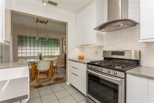 kitchen with wall chimney range hood, modern cabinets, white cabinets, and gas range