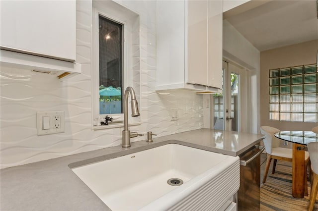 kitchen with white cabinets, a sink, dishwasher, and light stone countertops