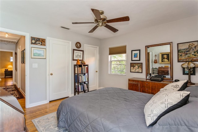 bedroom featuring ceiling fan, wood finished floors, visible vents, and baseboards