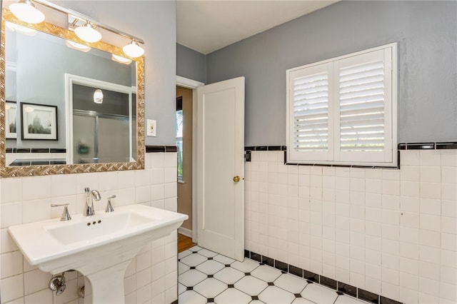 bathroom featuring a wainscoted wall, tile walls, a sink, a shower stall, and tile patterned floors