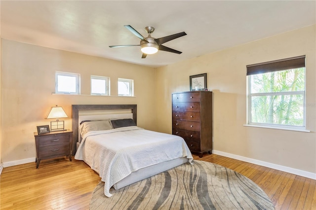 bedroom with ceiling fan, light wood finished floors, and baseboards