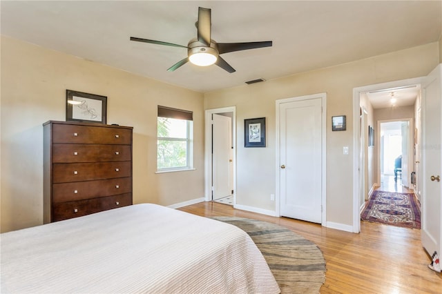 bedroom featuring light wood-style floors, baseboards, visible vents, and a ceiling fan