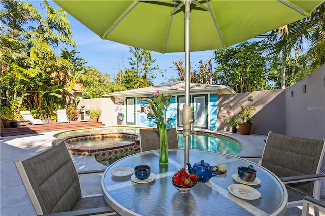 view of patio / terrace with outdoor dining space, a fenced in pool, a fenced backyard, and an in ground hot tub