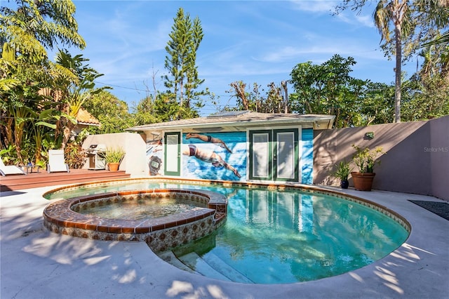 view of swimming pool featuring a wooden deck, fence, and a pool with connected hot tub