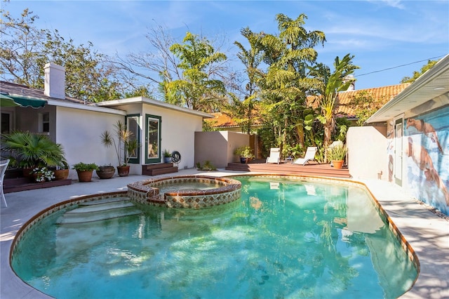 view of swimming pool featuring a pool with connected hot tub and fence