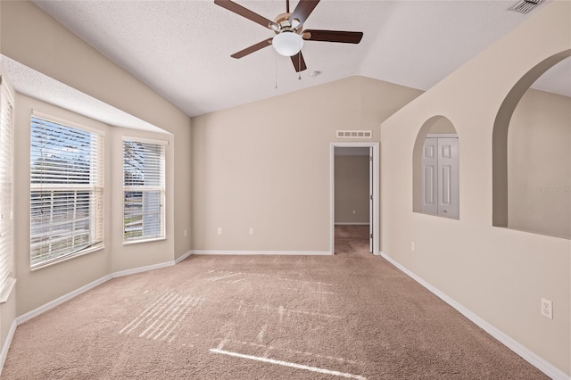 carpeted empty room with ceiling fan, vaulted ceiling, and a textured ceiling