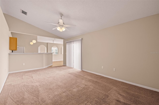 carpeted empty room featuring ceiling fan, vaulted ceiling, and a textured ceiling