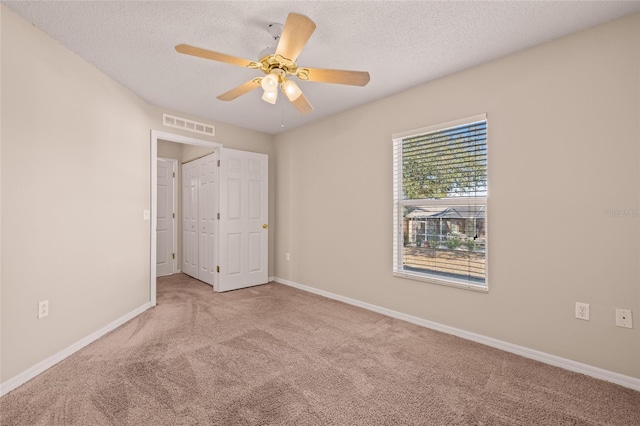 unfurnished bedroom featuring ceiling fan, light colored carpet, and a textured ceiling