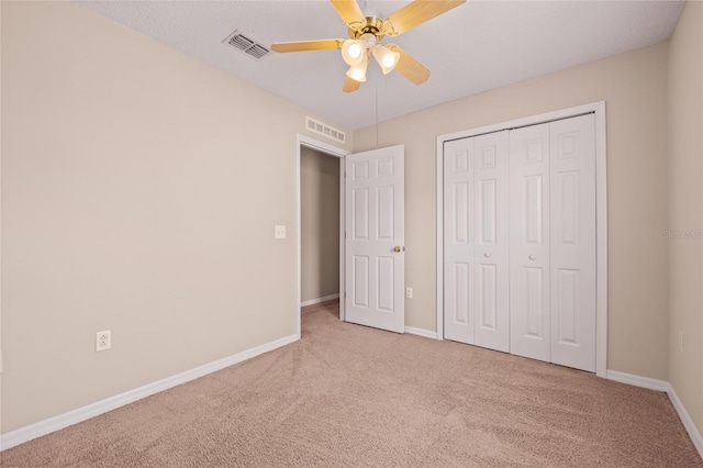 unfurnished bedroom featuring ceiling fan, light colored carpet, and a closet