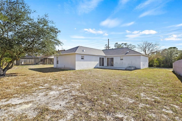 back of house with a yard and glass enclosure