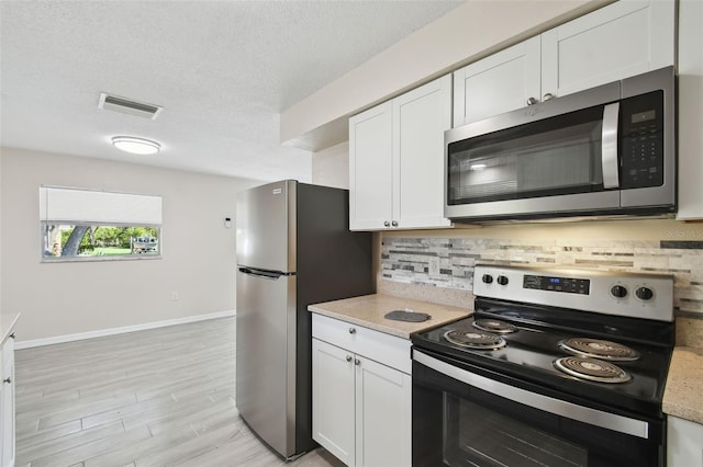 kitchen featuring white cabinetry, appliances with stainless steel finishes, a textured ceiling, and decorative backsplash