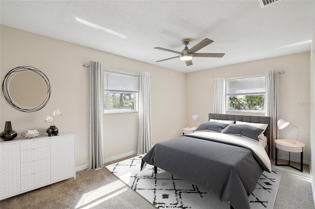 carpeted bedroom featuring multiple windows, a textured ceiling, and ceiling fan