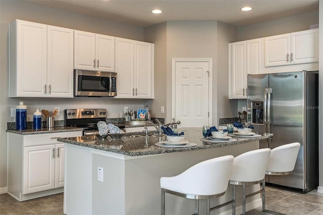 kitchen featuring stainless steel appliances, a center island with sink, and white cabinets