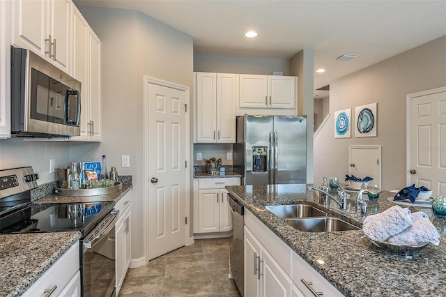 kitchen with dark stone countertops, appliances with stainless steel finishes, sink, and white cabinets