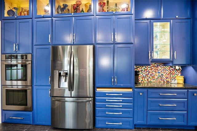 kitchen with dark stone counters, backsplash, stainless steel appliances, and blue cabinets