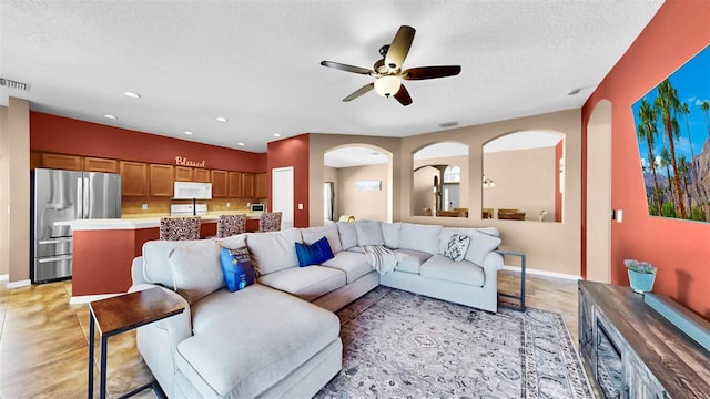 living room featuring ceiling fan and a textured ceiling