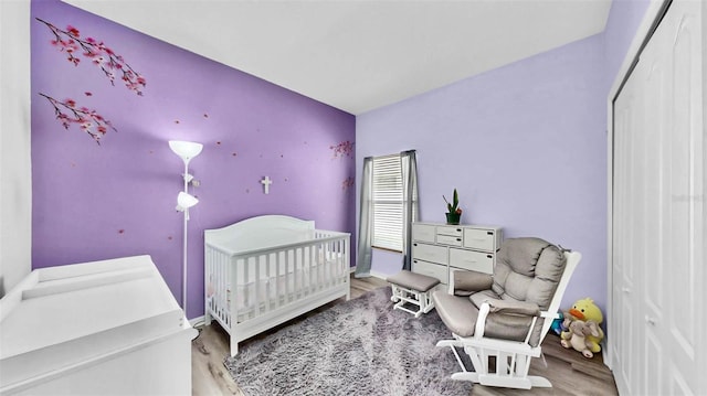 bedroom with a crib and wood-type flooring