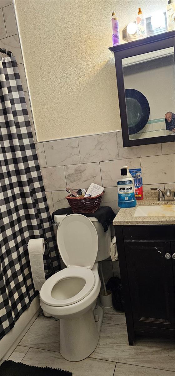 bathroom featuring vanity, tile walls, and toilet