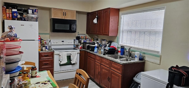 kitchen with light stone counters, white appliances, and sink