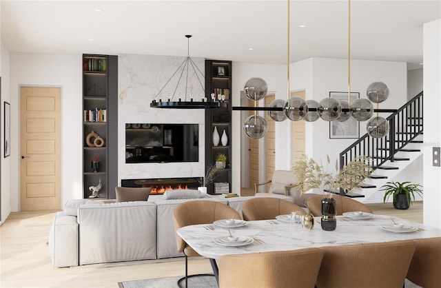 dining area featuring a premium fireplace, an inviting chandelier, and light wood-type flooring