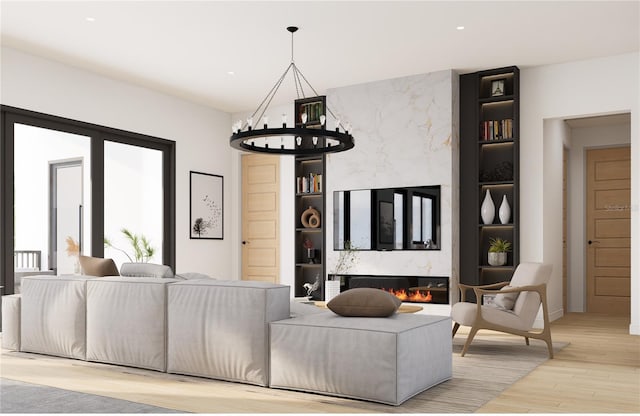 living room with a high end fireplace, a chandelier, and light hardwood / wood-style floors