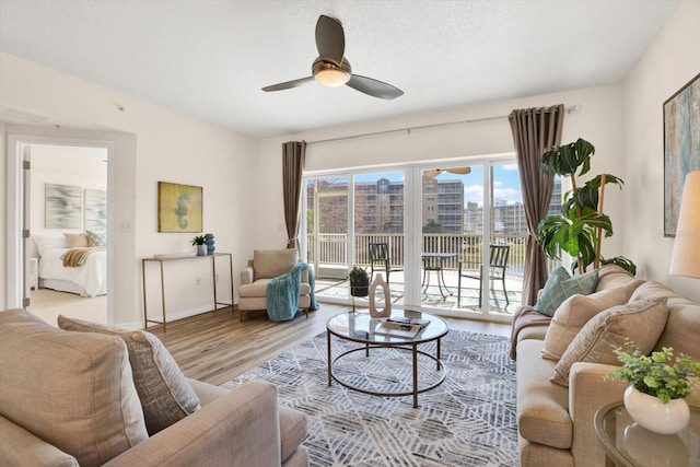 living room with ceiling fan, a textured ceiling, and light wood-type flooring