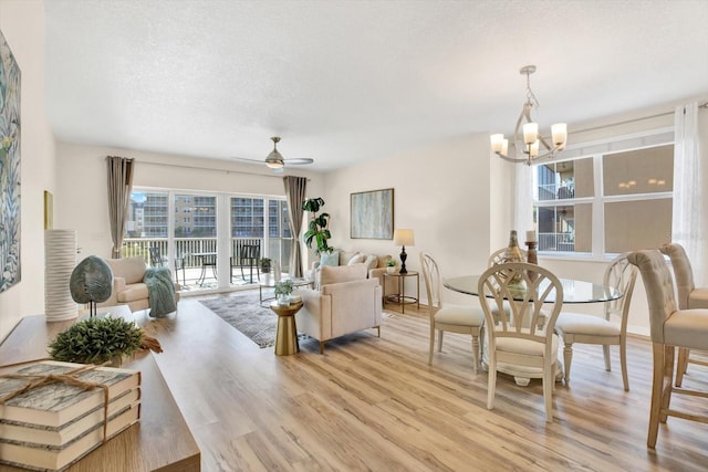 living room with ceiling fan with notable chandelier, a textured ceiling, and light hardwood / wood-style floors