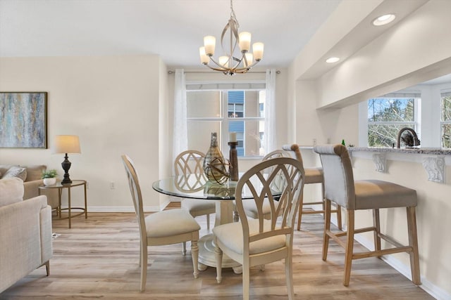 dining room with sink, an inviting chandelier, and light hardwood / wood-style flooring