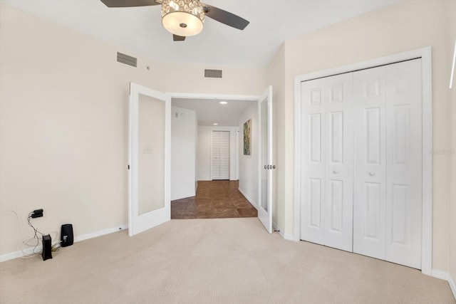 unfurnished bedroom with ceiling fan, light colored carpet, and a closet