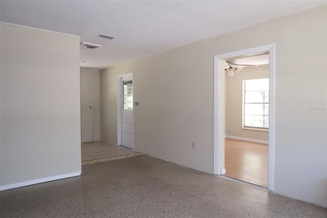 spare room with ceiling fan, visible vents, and speckled floor