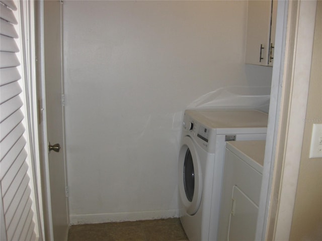 washroom featuring cabinets, dark tile patterned flooring, and washer and dryer