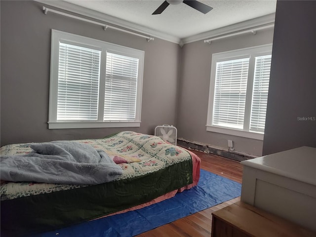 bedroom with crown molding, hardwood / wood-style flooring, a textured ceiling, and ceiling fan