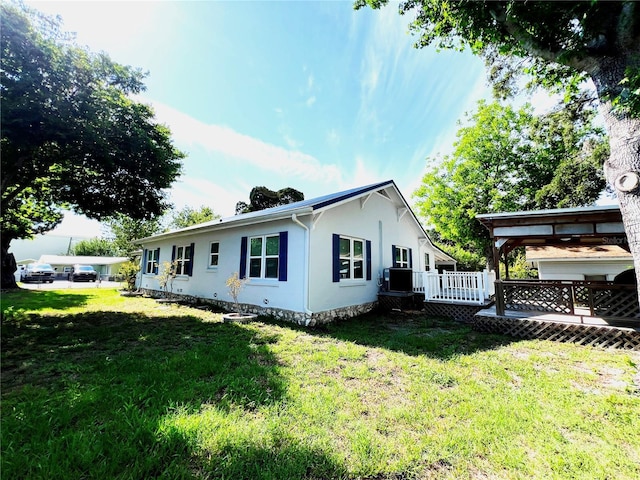 14124 Plum Ln, Hudson, FL 34667 - back of house with a deck, stucco siding, a lawn, and central air condition unit