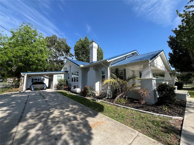 14124 Plum Ln, Hudson, FL 34667 - view of property exterior with concrete driveway, a chimney, metal roof, and an attached carport
