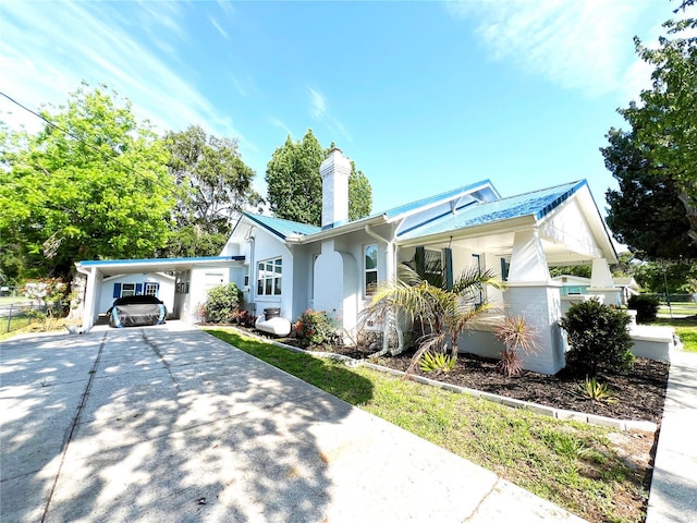 14124 Plum Ln, Hudson, FL 34667 - view of front of property featuring driveway, a chimney, metal roof, and a carport