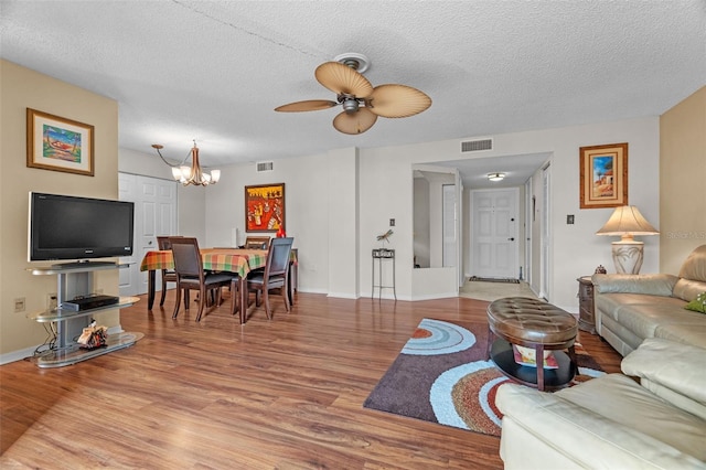 living room featuring hardwood / wood-style flooring, ceiling fan with notable chandelier, and a textured ceiling