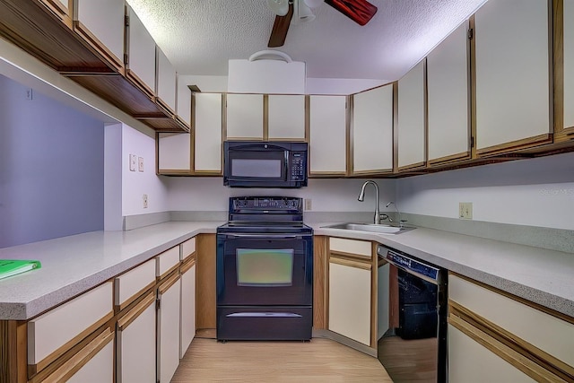 kitchen featuring white cabinetry, sink, black appliances, a textured ceiling, and light hardwood / wood-style flooring