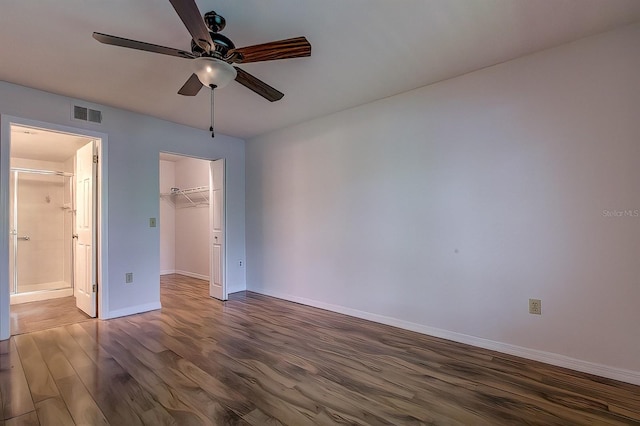 unfurnished bedroom featuring connected bathroom, a walk in closet, dark hardwood / wood-style flooring, a closet, and ceiling fan