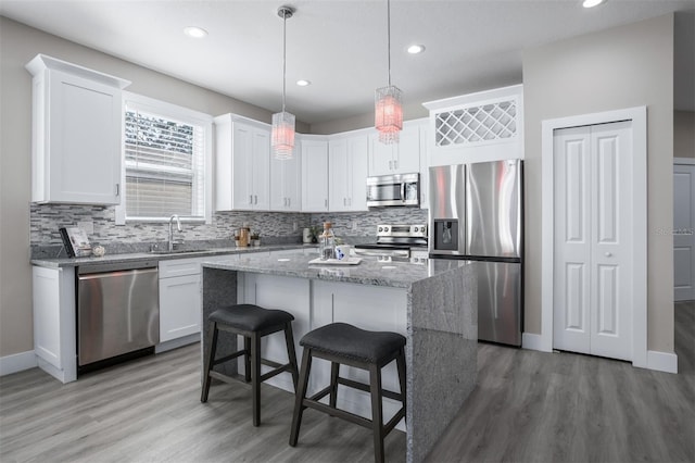 kitchen with hanging light fixtures, white cabinetry, appliances with stainless steel finishes, and a center island