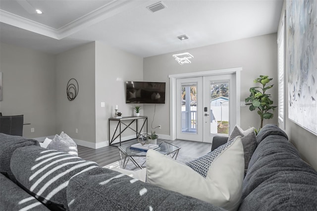 living room featuring hardwood / wood-style flooring, crown molding, and french doors