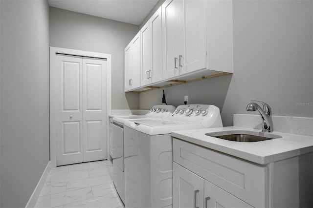 clothes washing area featuring cabinets, sink, and independent washer and dryer