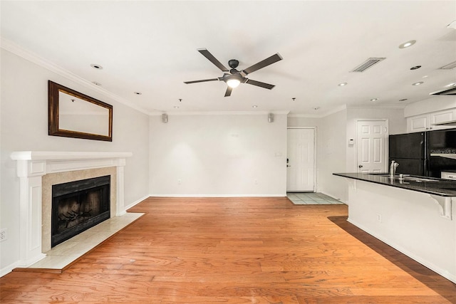 unfurnished living room with ceiling fan, ornamental molding, sink, and light hardwood / wood-style floors