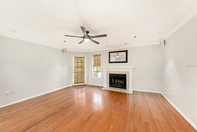 unfurnished living room featuring a fireplace, ornamental molding, ceiling fan, and light wood-type flooring