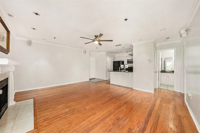 unfurnished living room with crown molding, ceiling fan, a fireplace, and light hardwood / wood-style floors