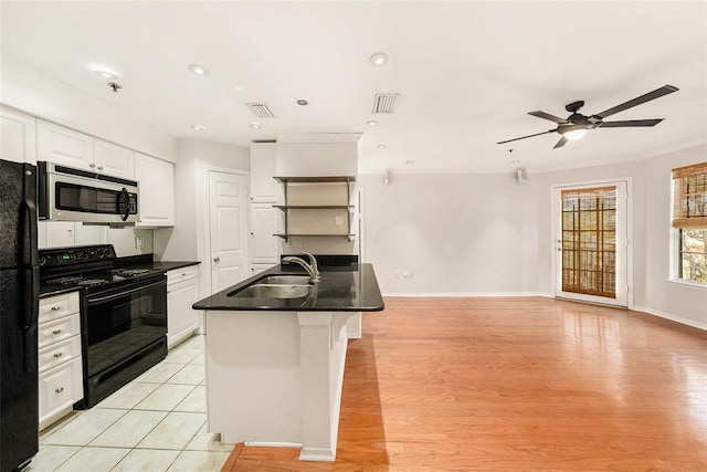 kitchen featuring sink, light hardwood / wood-style flooring, black appliances, white cabinets, and a center island with sink